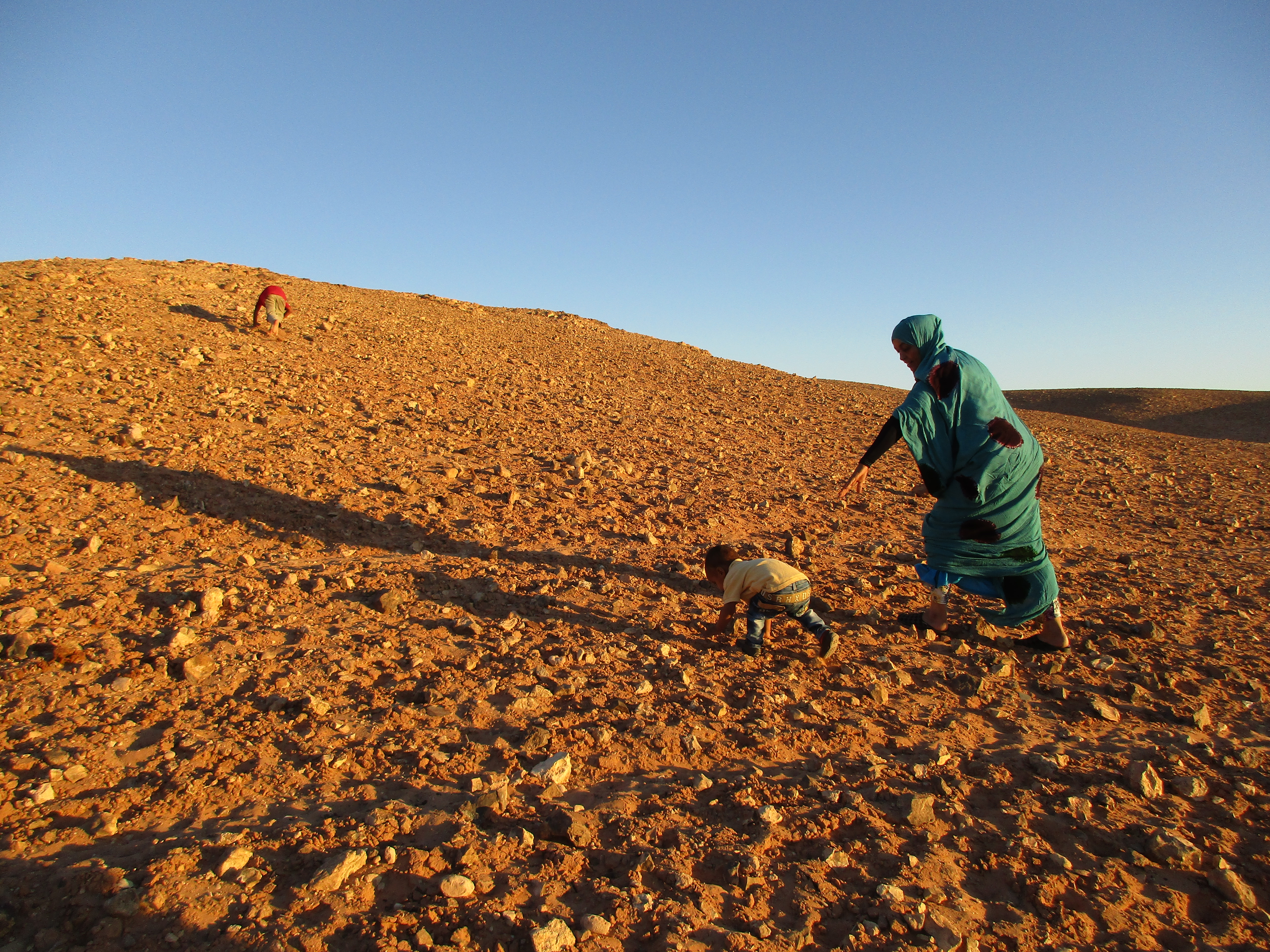 Najats søster og nevø bestiger bakken bag familliens hus i udkanten af Bojador-distriktet. I Algeriets stenørken er der intet livsgrundlag, og flygtningene har i 40 år overlevet på nødhjælpsrationer som en nation på kunstigt åndedræt. Foto: Camilla Tiefensee Schrøder 